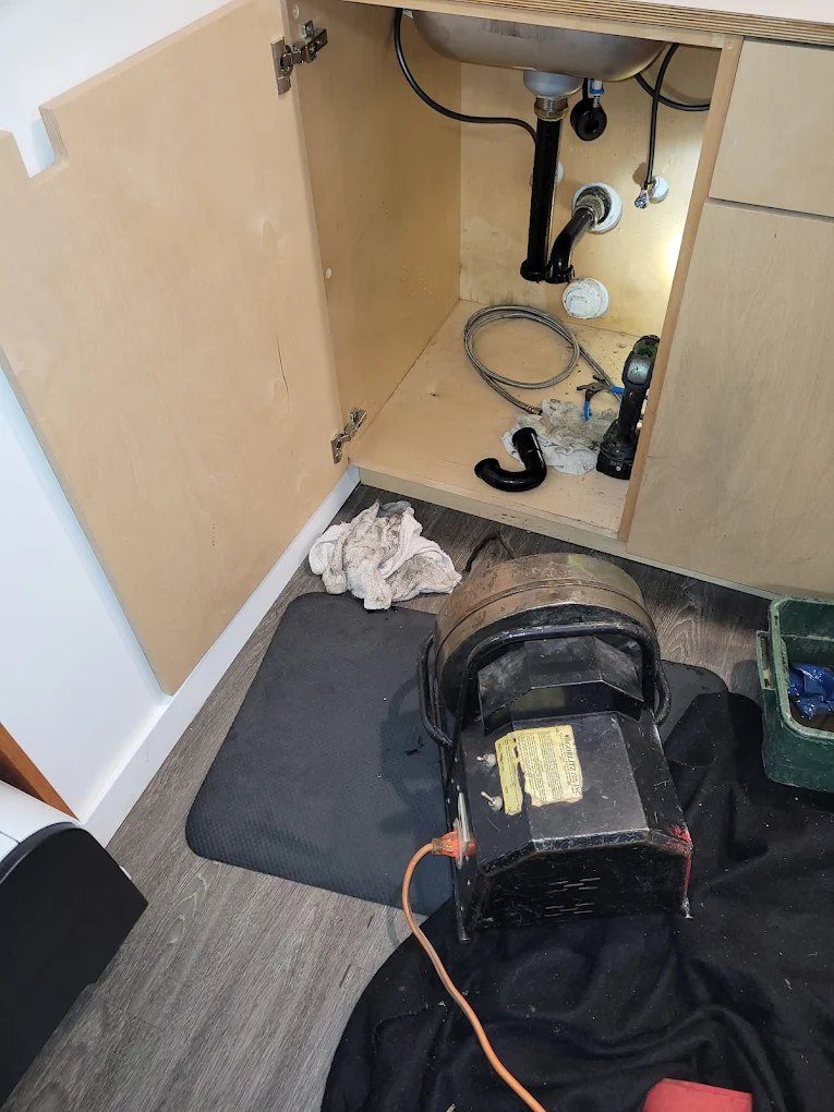Under-sink plumbing installation with pump motor and drainage pipes visible inside cabinet
