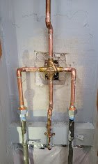 Copper and brass plumbing pipes with valves mounted on white wall