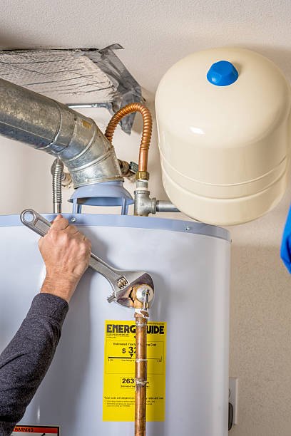 Plumber adjusting water heater expansion tank connection with wrench